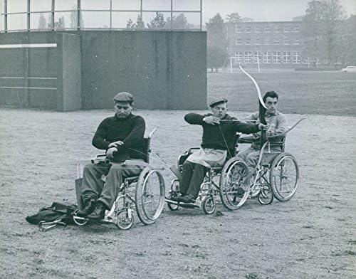 Foto vintage de homens em sua cadeira de rodas, cada um segurando um arco e flecha.- 1964
