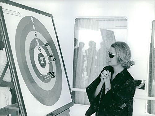 Foto vintage de Grace Kelly olhando para uma placa de dardo.